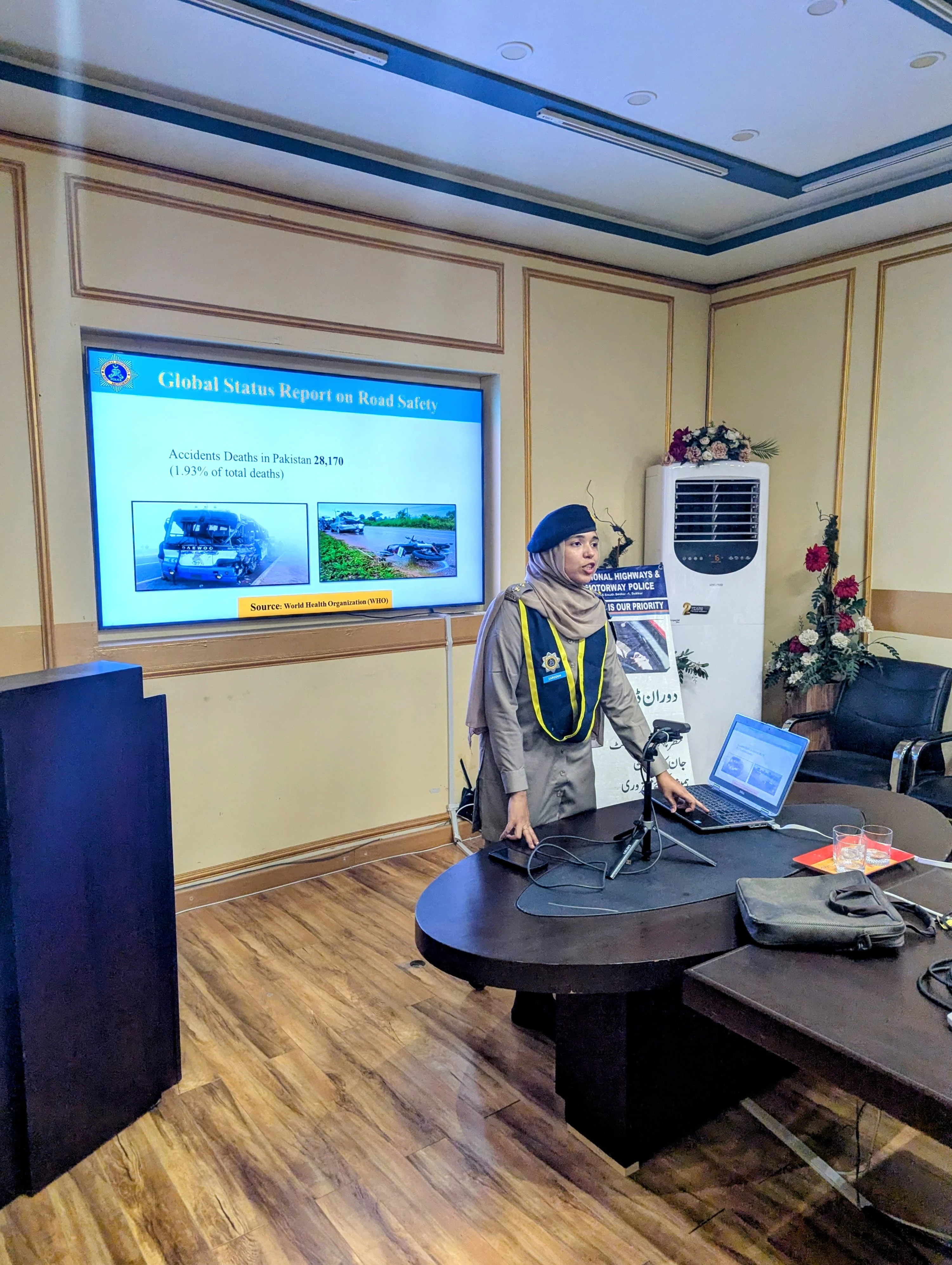 Zarqoon Saeed standing at a podium beside a Global Status Report on Road Safety briefing slide